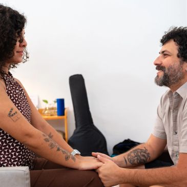 Couple holding hands and looking at each other with affection indoors.
