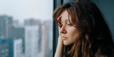 Woman looking thoughtfully out a rainy window.