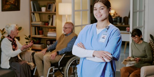 Smiling nurse in front of elderly patients in a care home.