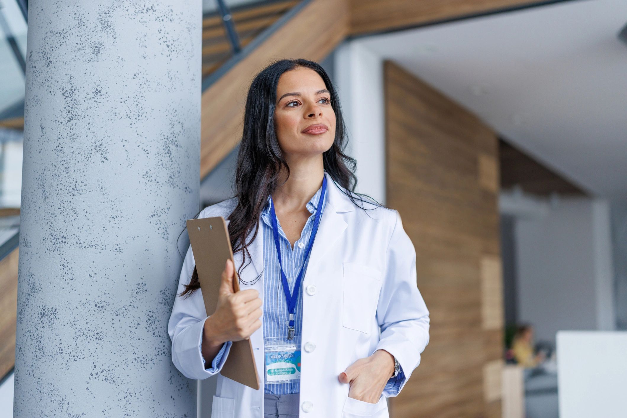 Female doctor holding a clipboard and looking thoughtful.