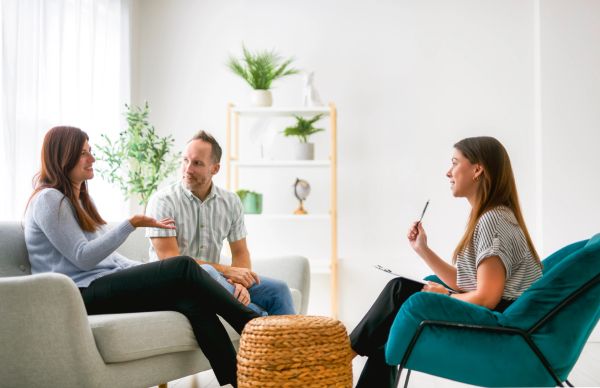 Couple consulting a female therapist in a bright room.