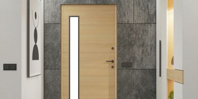 Modern wooden door with vertical glass panel in a sleek, minimalist hallway.