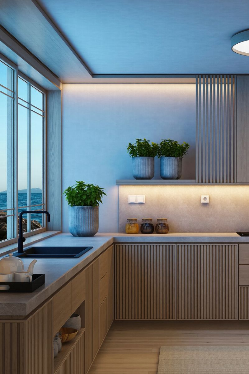 A modern Japandi style kitchen featuring vertical pine wood cabinetry, a light stone counter top, and a neutral color palette that emphasizes simplicity and natural warmth. Dusk blue light streams through large windows, enhancing the textures and materials while creating a calm, inviting atmosphere. Subtle decorative elements—such as ceramic vessels, candles, and clean-lined accessories—add character without disrupting the minimalist flow. This image is ideal for showcasing modern kitchen design, lifestyle content focused on slow living, or editorial features highlighting natural materials and night dusk optimized interiors.