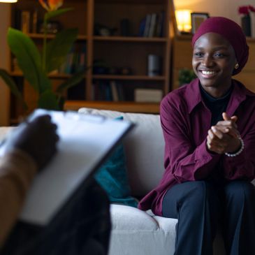 A smiling woman in a hijab during a counseling session.