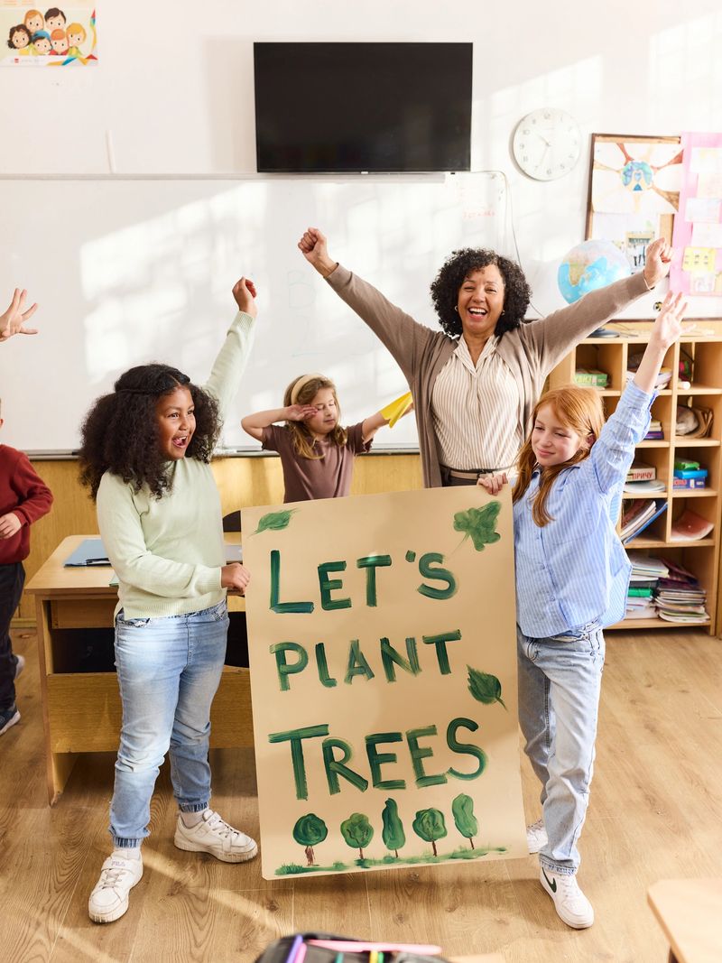 Cheerful female teacher and her students having fun while celebrating the activity of planting the trees in the classroom.