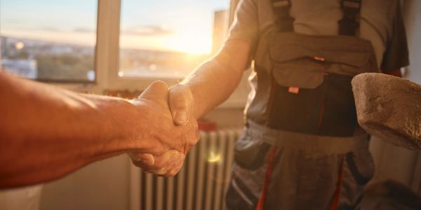 Two people shaking hands indoors with sunlight in the background.