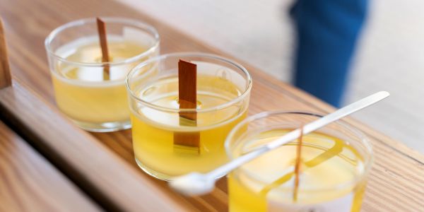 Three yellow candles with wooden wicks on a wooden tray.