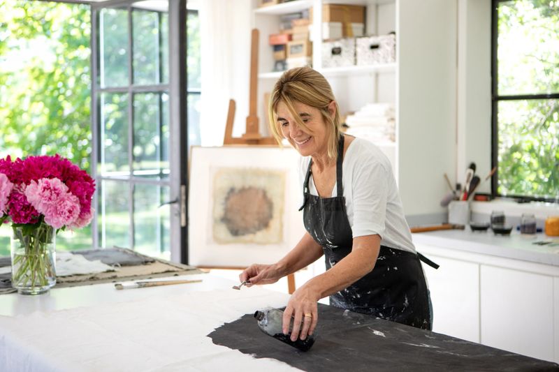 Mature entrepreneurial woman working in her art studio, pouring paint onto a canvas - Buenos Aires - Argentina