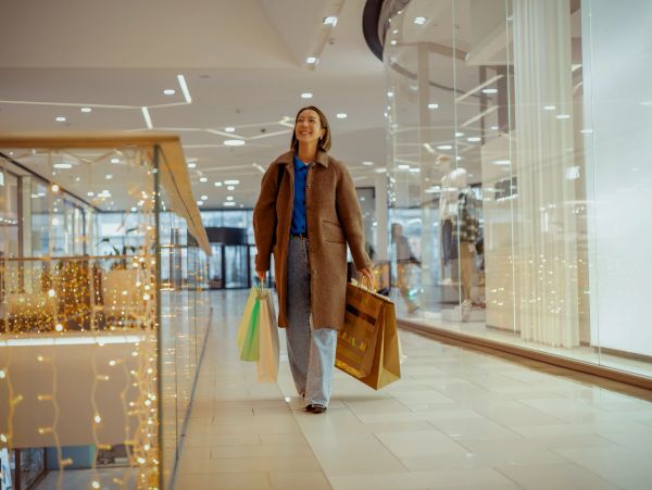 Smiling woman walking in mall with shopping bags.