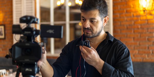 Man adjusting audio equipment on camera in a cozy room.