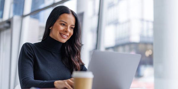 Woman working on laptop with coffee nearby.
