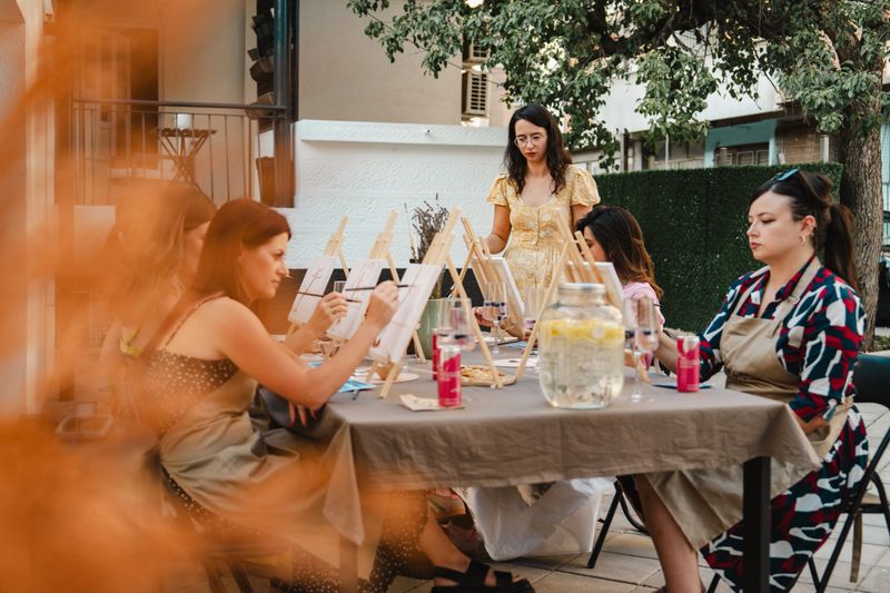A group of friends enjoys an outdoor painting class, creating art and socializing together