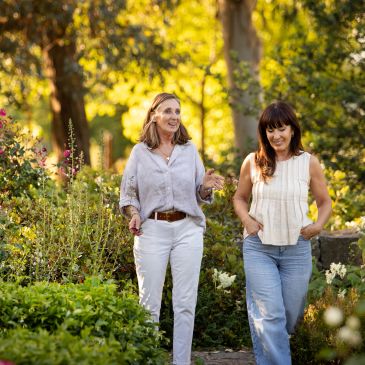 Two women walking and talking in a garden.
