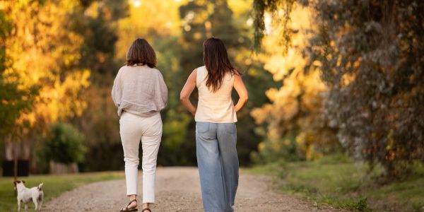 Two women walking with a dog on a scenic path.