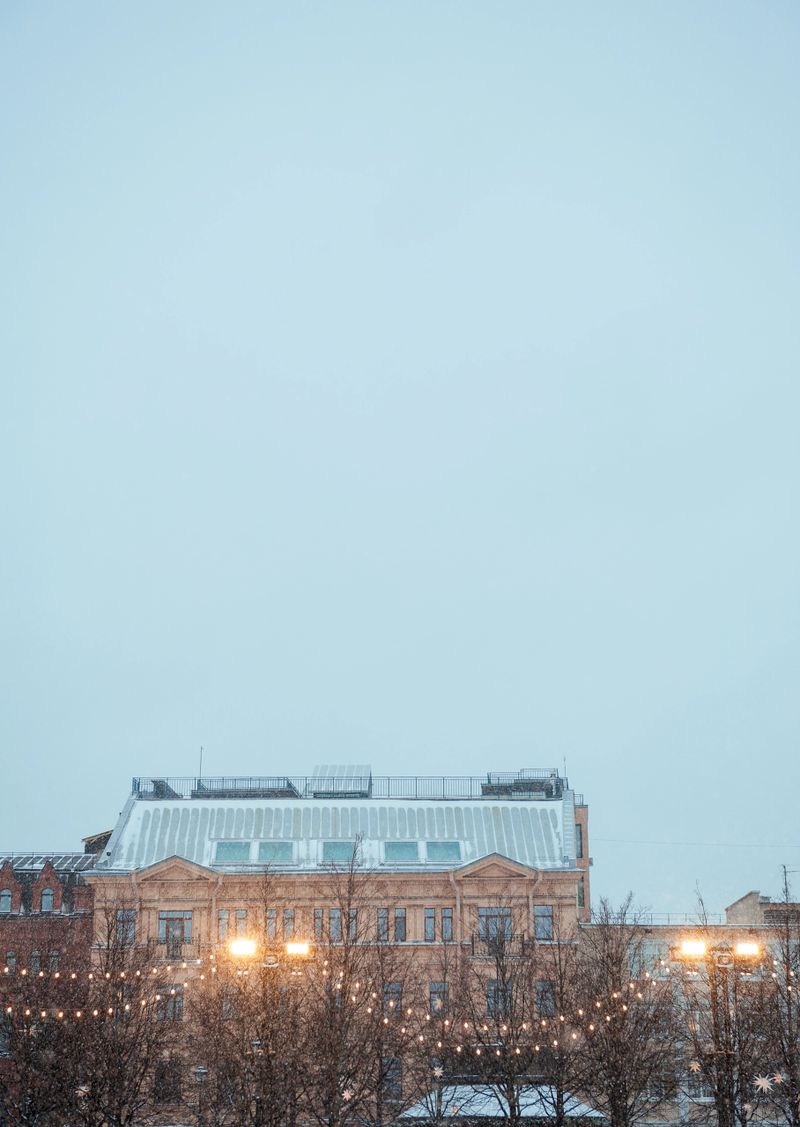 Festive string lights glow against historic city buildings. Urban evening scene captures cozy winter atmosphere