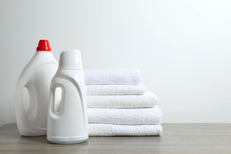 A stack of freshly washed towels and washing products on a table