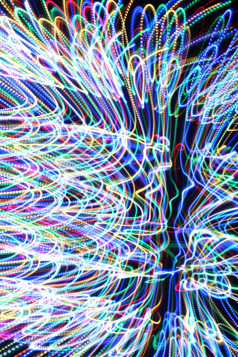 Long exposure light painting photograph, vibrant colour against a black background