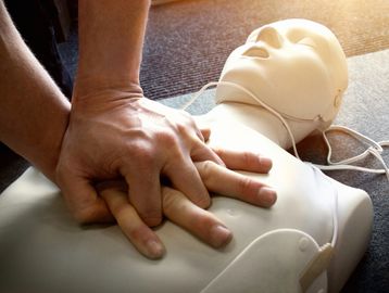 Hands performing CPR on a training dummy.