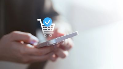 Person using smartphone for online shopping with a confirmation icon.