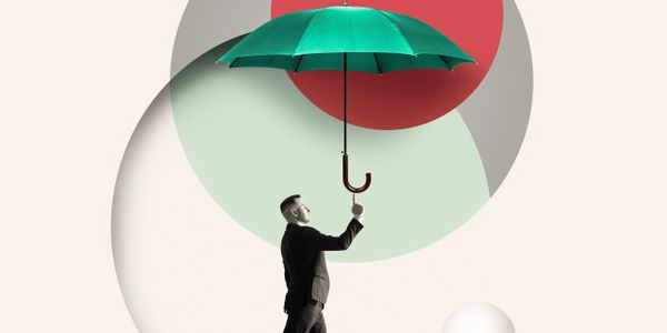 Man in suit holding a green umbrella with abstract circles in background.