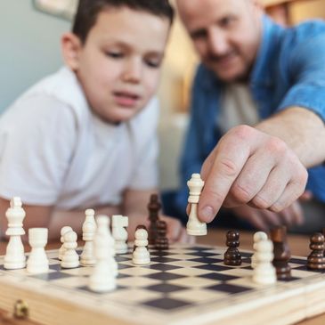 Dad teaching son to play chess.