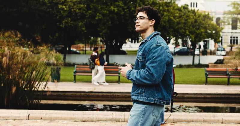 Smartphone, thinking and university with man, student and website info for scholarship. Outdoor, college and person with ideas, choice and cellphone with social media, problem solving and solution