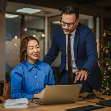 Two colleagues collaborating over a laptop in an office setting.