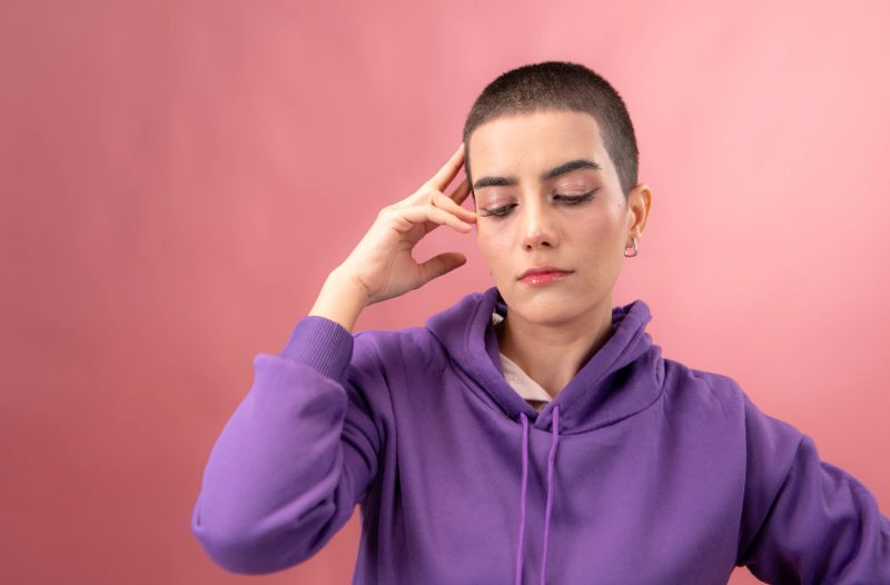 Portrait of young woman cheerful young woman with a buzz cut smiling confidently against a pink background