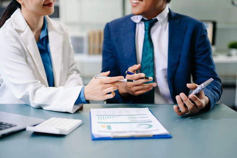 Professional businesspeople analyzing data, discussing strategy, and collaborating on financial reports in a modern corporate office setting.