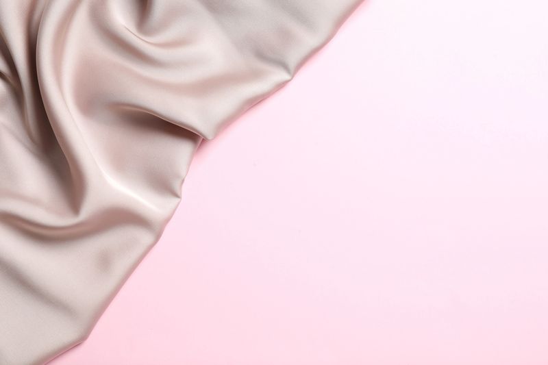 Beige silk satin. Shiny smooth fabric. Soft folds. Luxury background with space for design