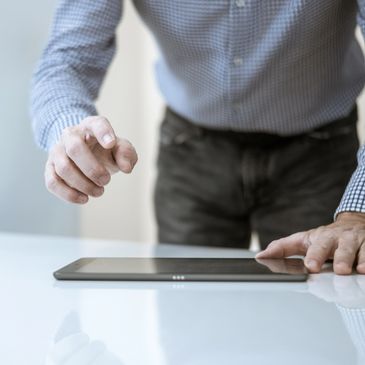 Man interacting with a tablet on a white table.