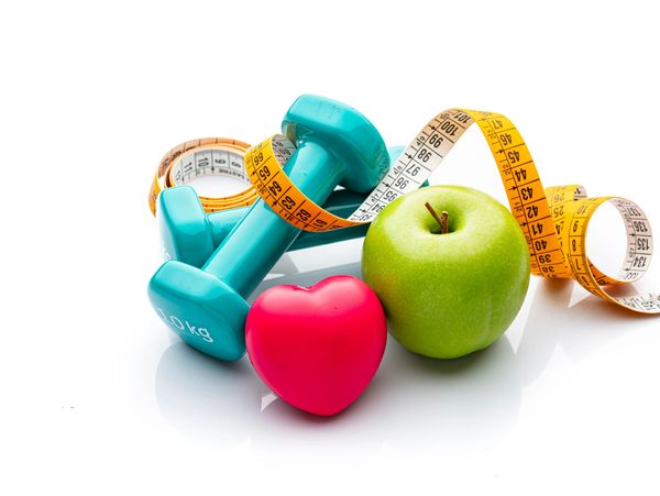 Dumbbells, measuring tape, apple, and heart for fitness.