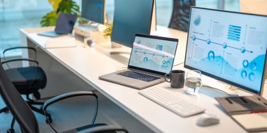 Modern office setup with laptops and monitors displaying data analytics.