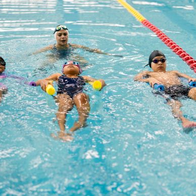 Kids learning to swim with instructor in the pool.