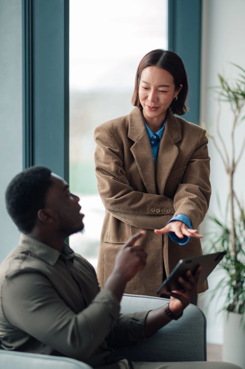 Diverse business colleagues engaged in discussion, collaborating on a digital tablet in a modern office meeting setting