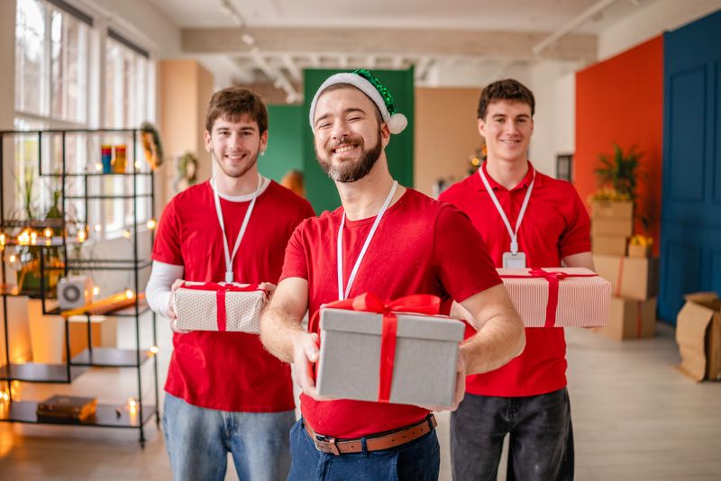 A group of volunteers is packing Christmas presents for children at a local community center. They are smiling and working as a team to spread holiday cheer.