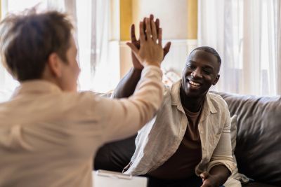 Two men giving a high five on a couch.