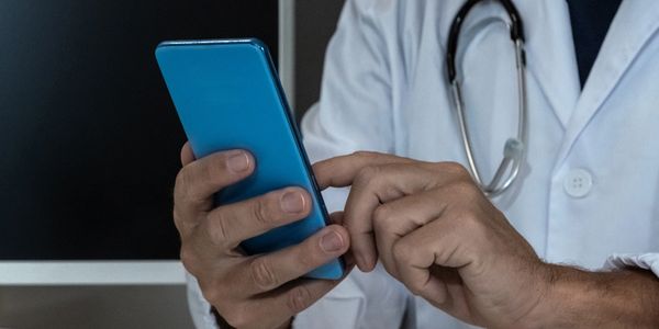 Doctor using a smartphone, wearing a white coat and stethoscope.