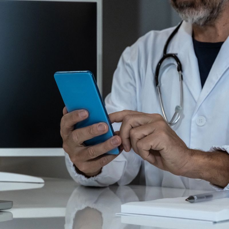 Doctor engaging with a smartphone in a modern medical setting, seamlessly integrating digital tools into patient care