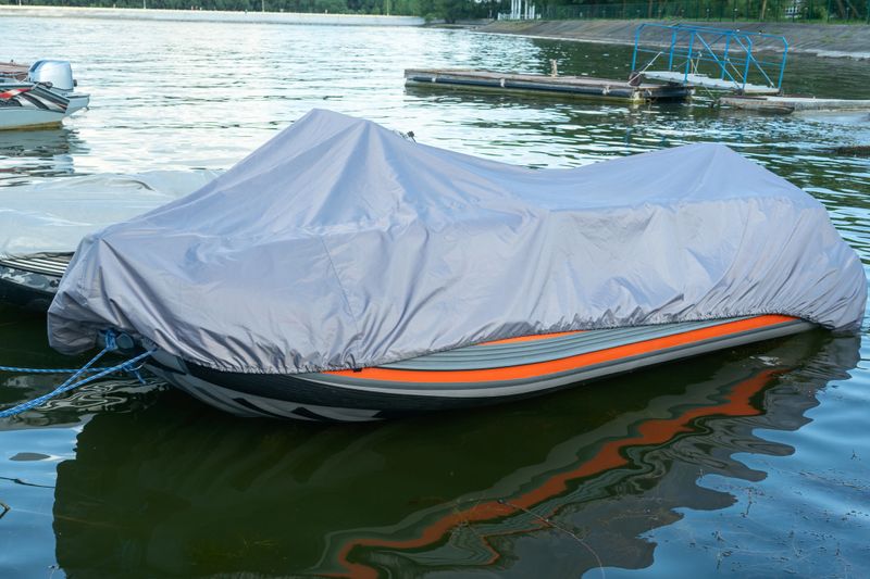 A covered boat at the pier longing for the sun and the thrill of adventure on the water. Boat sheltered on the pier waiting for the perfect weather to sail.