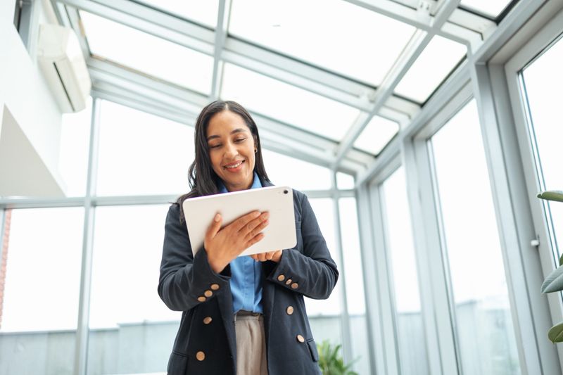 Businesswoman looking at a digital tablet device while working in a bright, contemporary corporate office environment