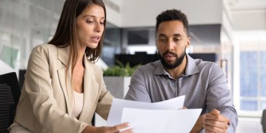 Two colleagues reviewing documents in an office.