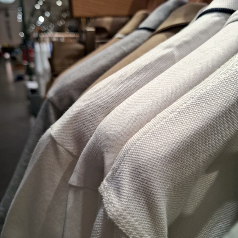 Close up of high quality textured cotton polo shirts hanging on display rack in luxury clothing store with soft bokeh background lighting for fashion retail concept
