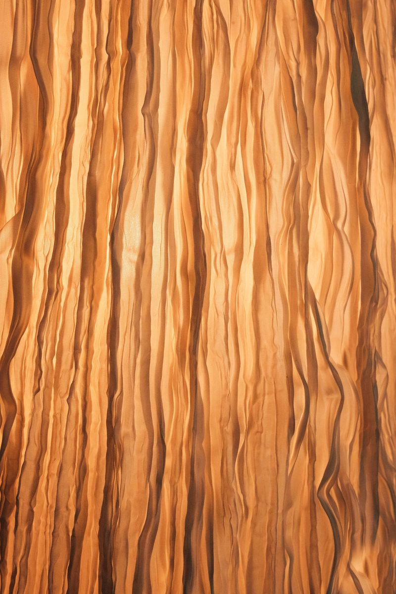 Artistic close-up of a fabric lampshade with warm backlight, showing vertical textured folds that create a soft, cozy and decorative abstract background.