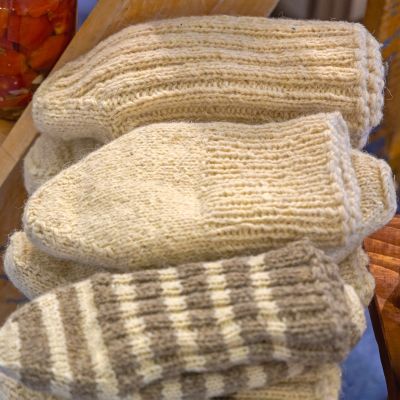 Hand-knit wool mittens in cream and striped patterns.