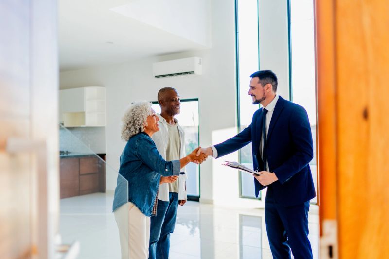 Senior couple closing deal with real estate agent at house
