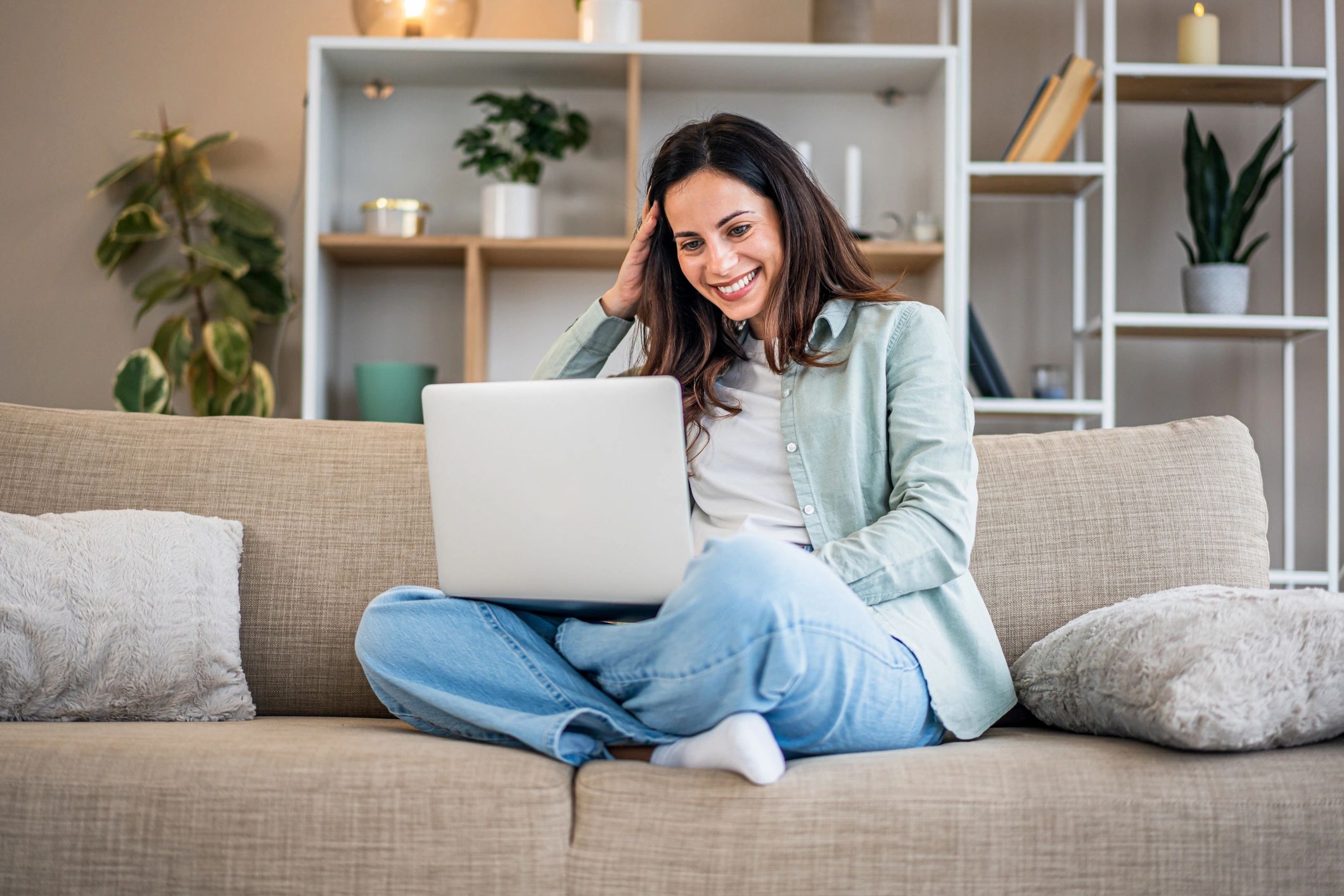 Mujer feliz usando una computadora portátil en el sofá.