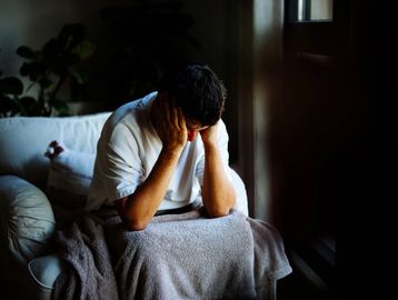 Person sitting with head in hands, appearing distressed.