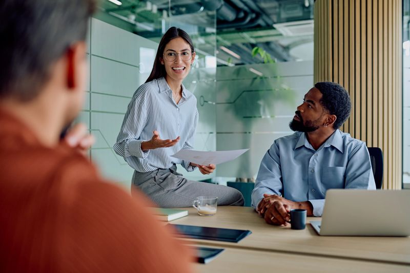 Professionals collaborating during a meeting in a modern office, a woman presenting ideas to her attentive colleagues
