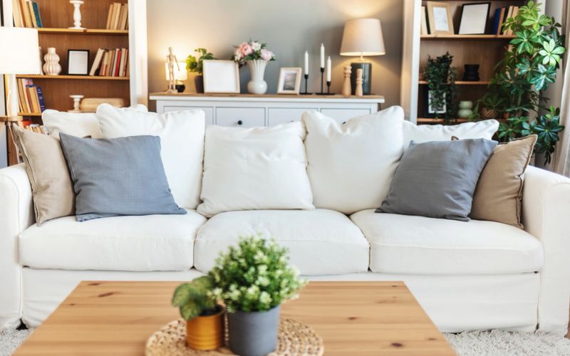 Modern living room showcasing a white sofa, stylish bookshelves filled with books, elegant lamps, and decorative items, creating a cozy and inviting atmosphere perfect for relaxation.